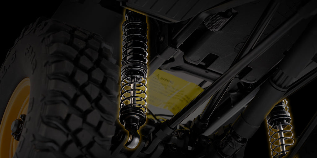 a black coil-over shock absorber on the suspension of an RC rock crawler