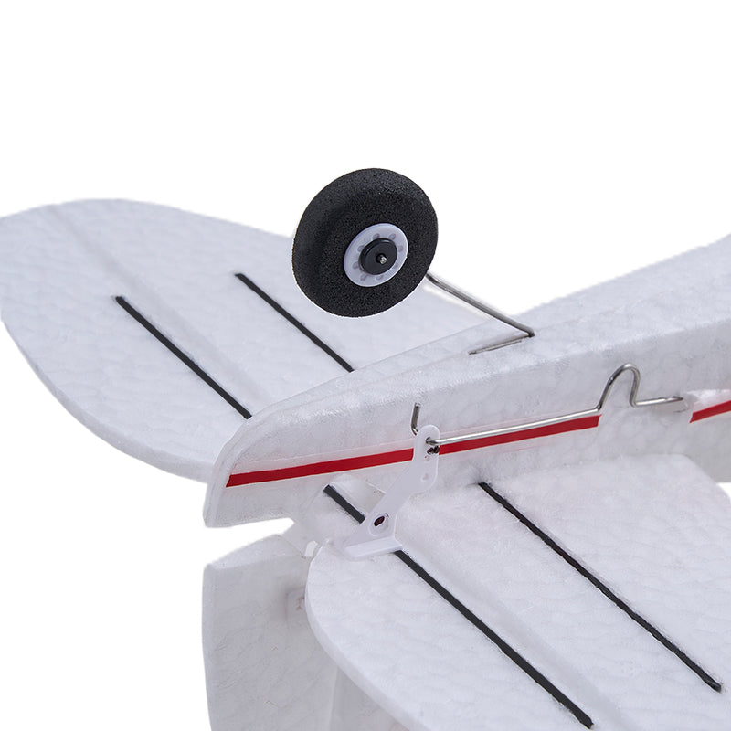 Close-up of the white FMS 500mm PA-18 Super Cub RC plane's white foam wing and landing gear wheel with black tire.