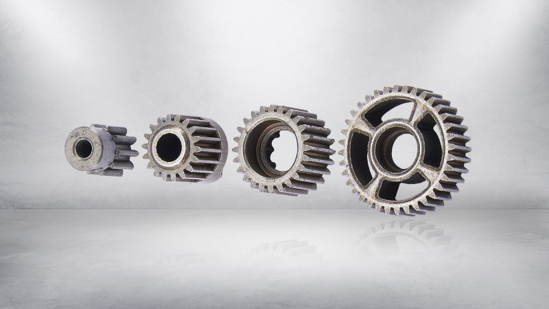 A lineup of four different-sized steel gears manufactured using a powder metallurgy process