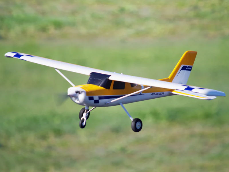FMS 1220mm Ranger high-wing RC trainer plane flying over a grass field