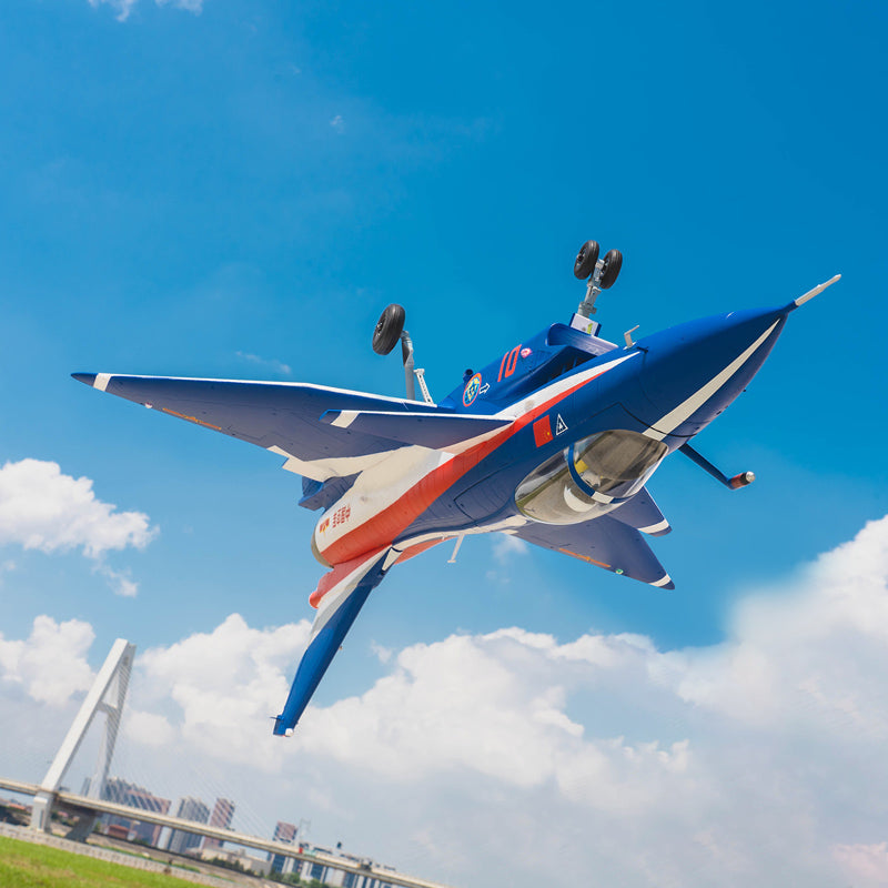 FMS EDF Jet 64mm J-10 model flying, blue with red and white accents, landing gear down.