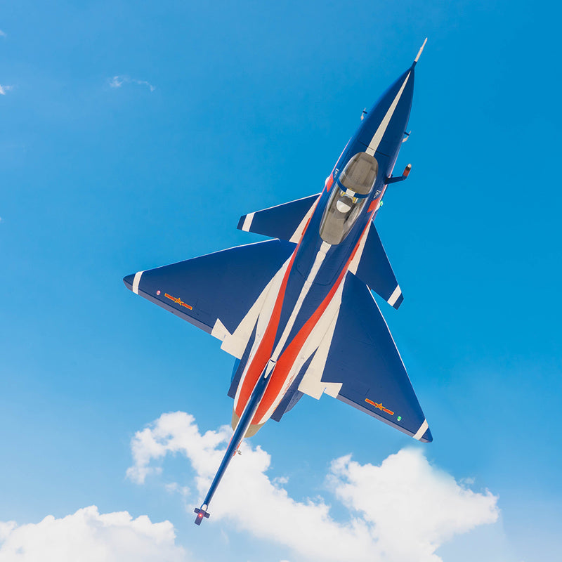 Blue FMS EDF J-10 jet with red and white racing stripes flying in a bright blue sky with white clouds.