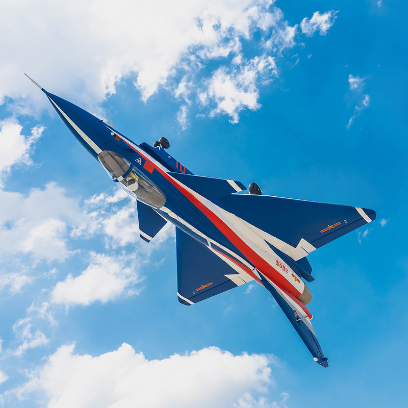 FMS EDF Jet 64mm J-10 PNP model airplane in blue, white, and red flying against a cloudy blue sky.