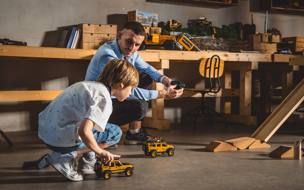 A father and son bond in their workshop while testing their scale Fmshobby RC Trucks on an indoor track