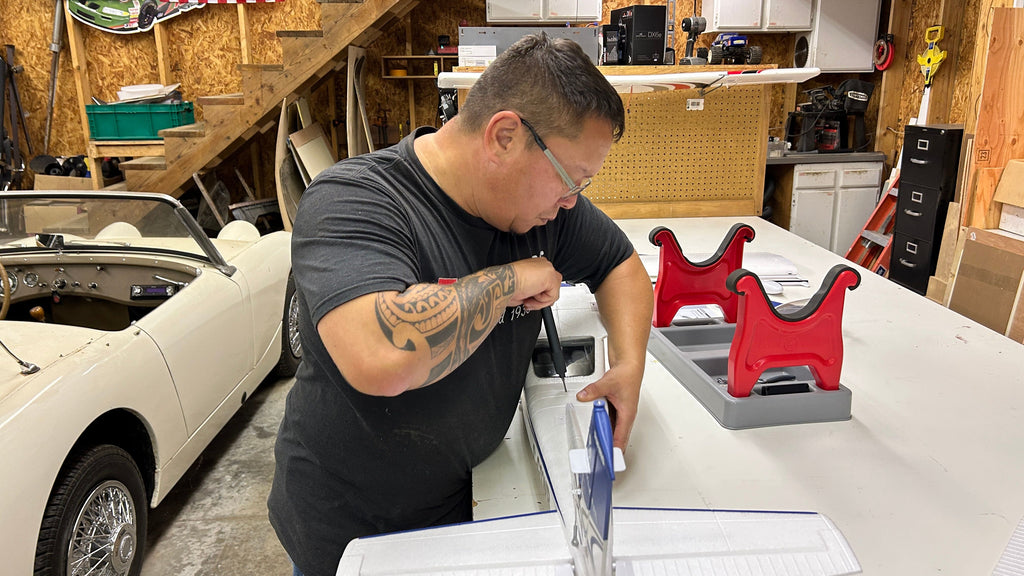 RC plane hobbyist assembling FMS Cessna model in workshop with classic car in background