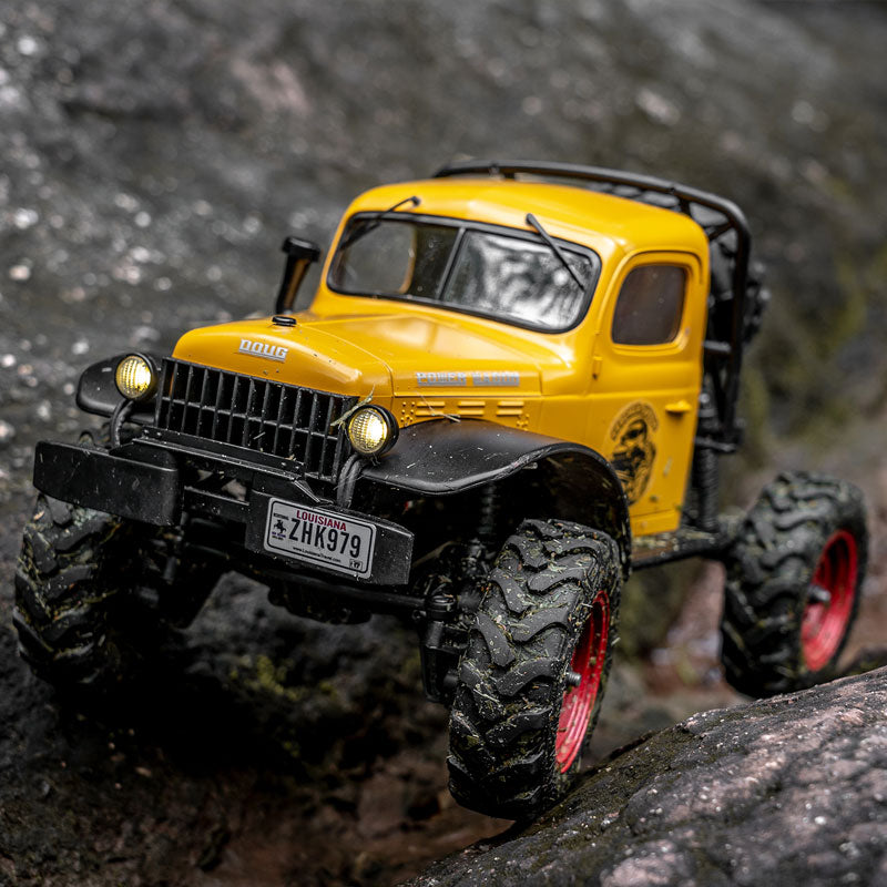 FMS 1:24 FCX24 Power Wagon RTR yellow remote control rock crawler on rocks with detailed features and aggressive tires.
