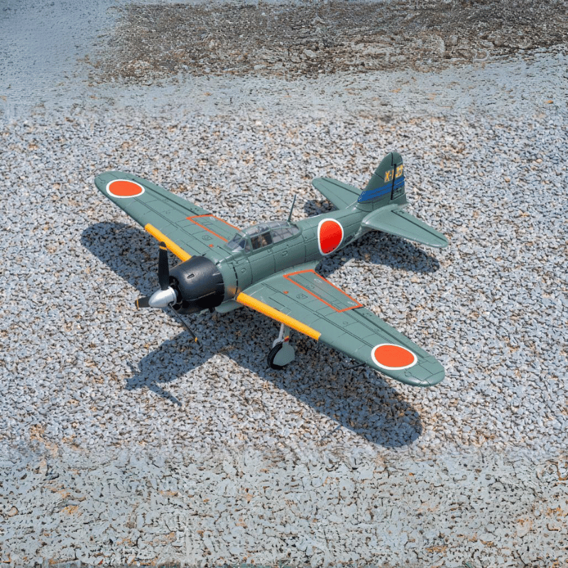 FMS 800mm Zero A6M3 V2 PNP airplane, green with red Hinomaru insignia and yellow wingtips, on gravel.