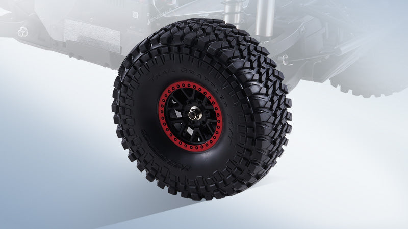 A Nitto Trail Grappler off-road tire mounted on a black wheel with a red beadlock ring
