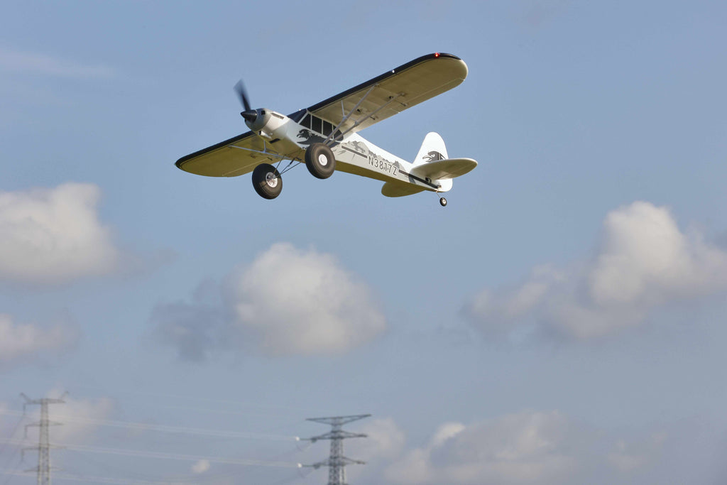 RC plane in flight with scattered clouds visible