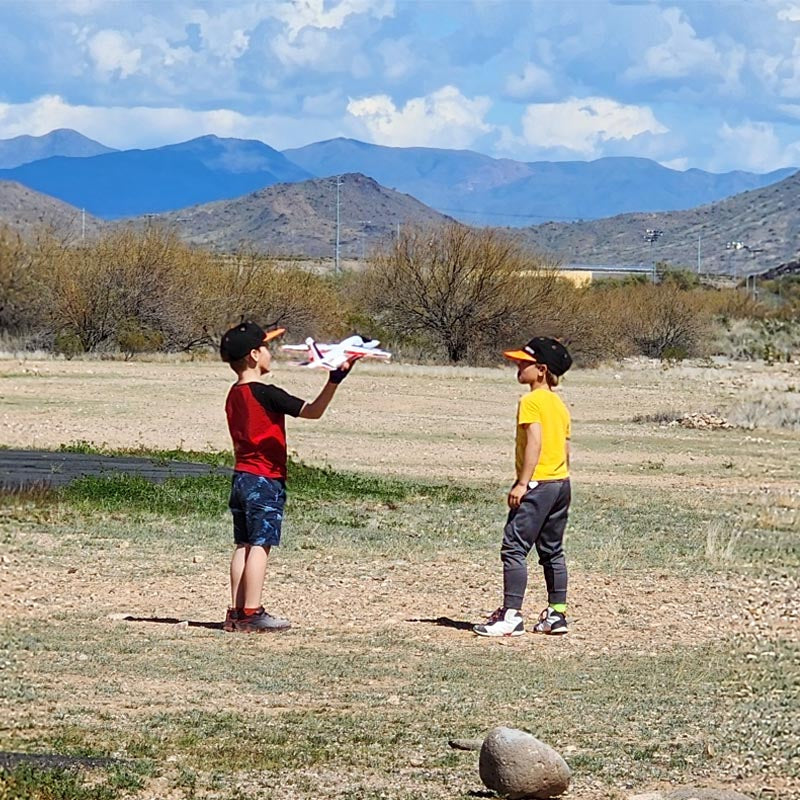 Children preparing to launch FMS Alpha Hand-Launched Jet Kit in a grassy area.