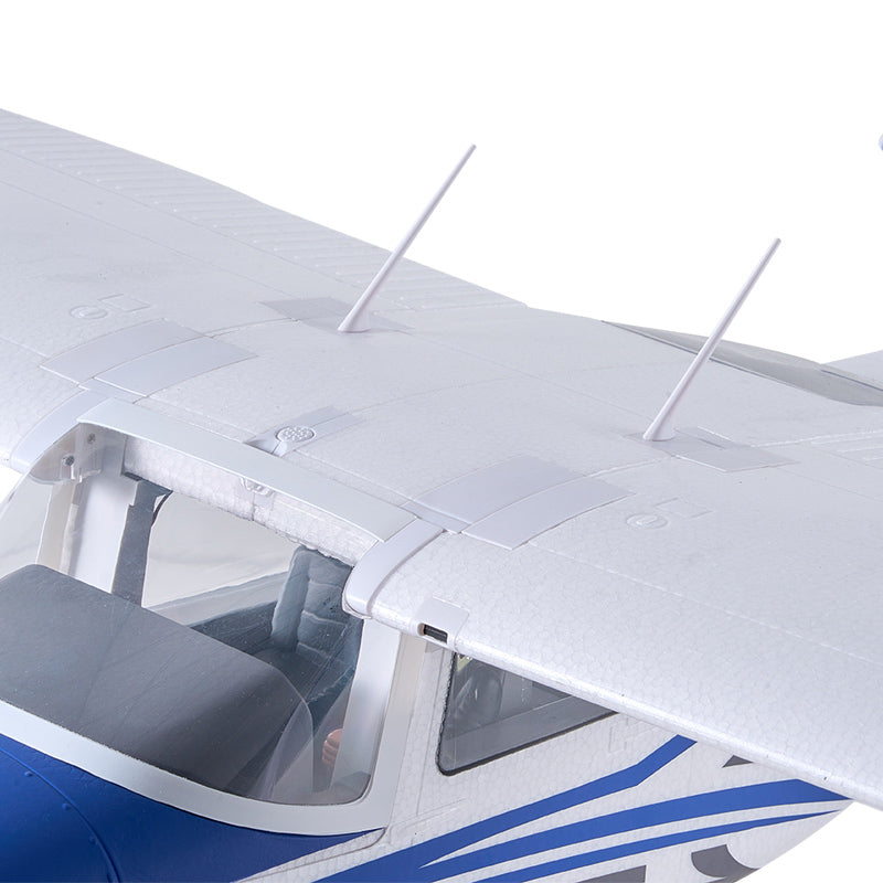 Close-up of the FMS 1500mm Cessna 182 RC airplane's white wing, showing two white antennas and detailing on the fuselage.