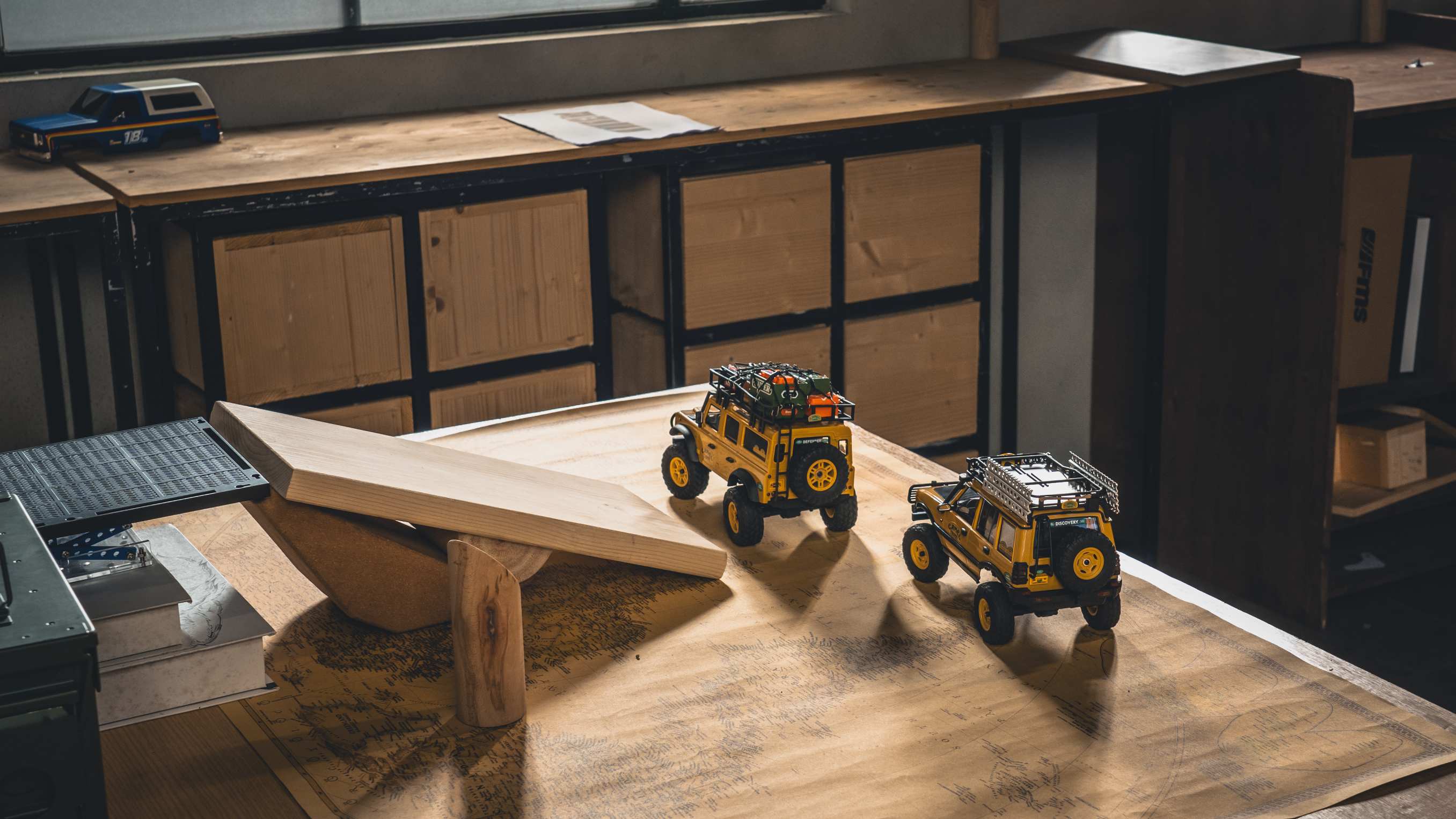 Two mini RC crawlers tackling a homemade indoor course built from a wooden plank ramp and see-saw
