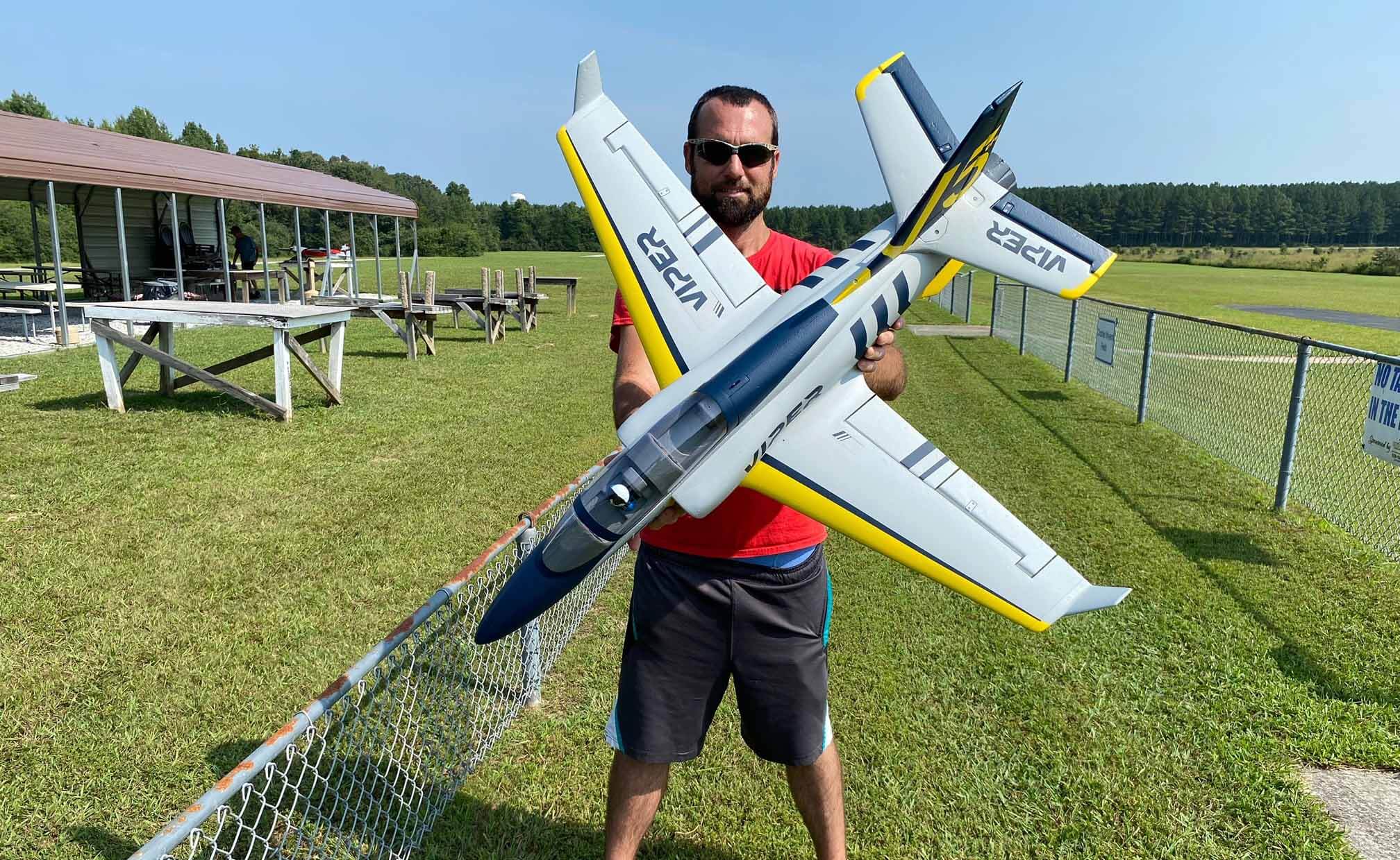 Pilot holding an FMS Viper R/C jet model at an outdoor flying site.