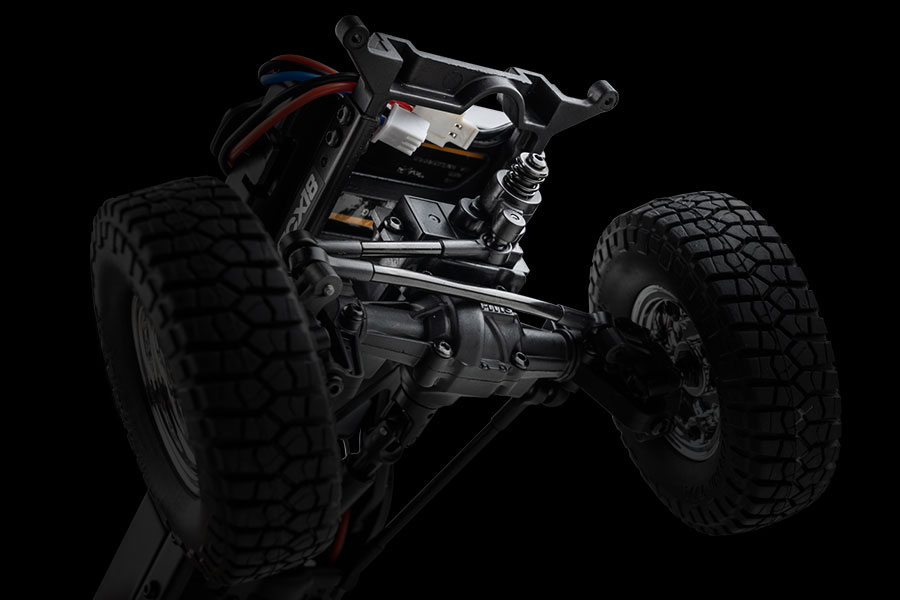 A close-up view of an RC crawler's front axle and suspension.