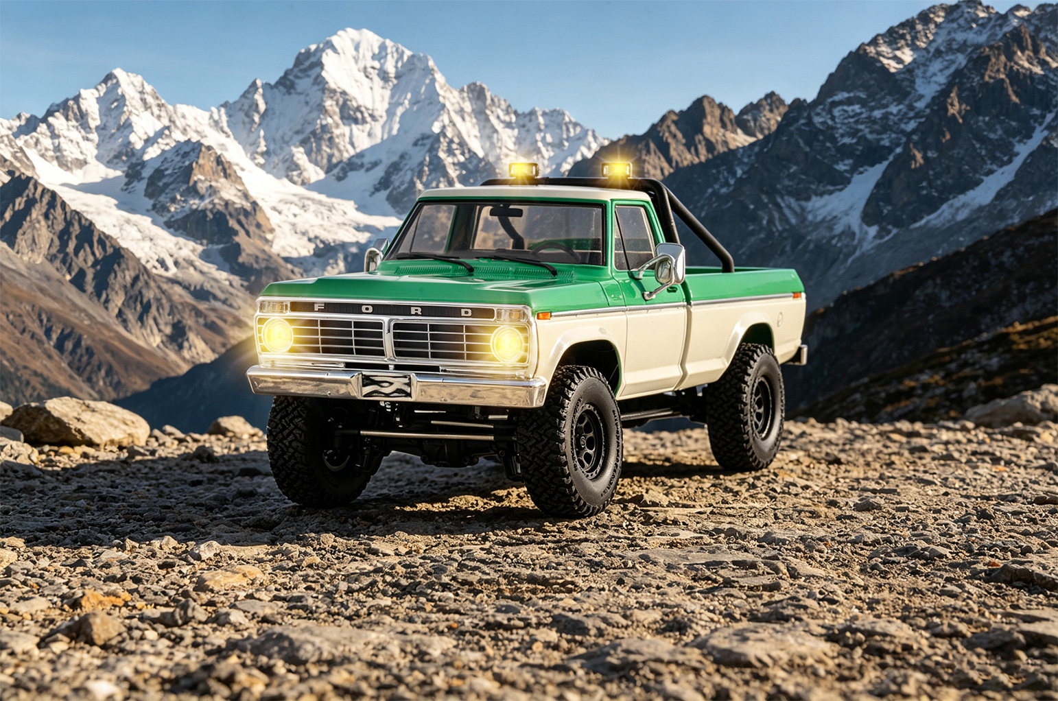 Green and white FMS FCX18 II Ford F-100 1/18 RC crawler on rocky ground below snow-capped mountains