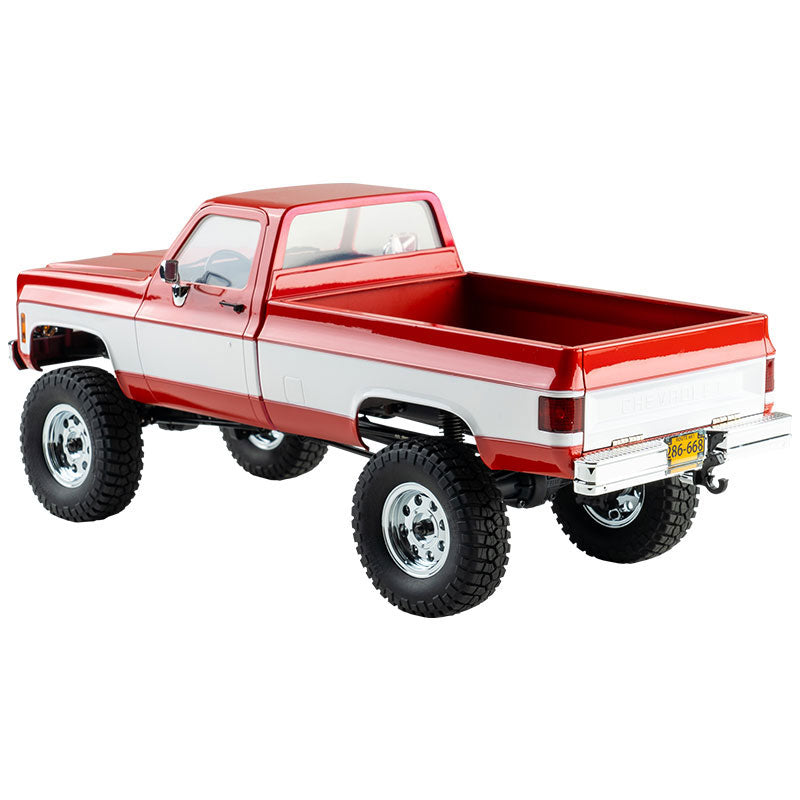 FMS 1:18 FCX18 Chevrolet K10 V2 RTR RC truck in red and white, featuring off-road tires and chrome wheels.
