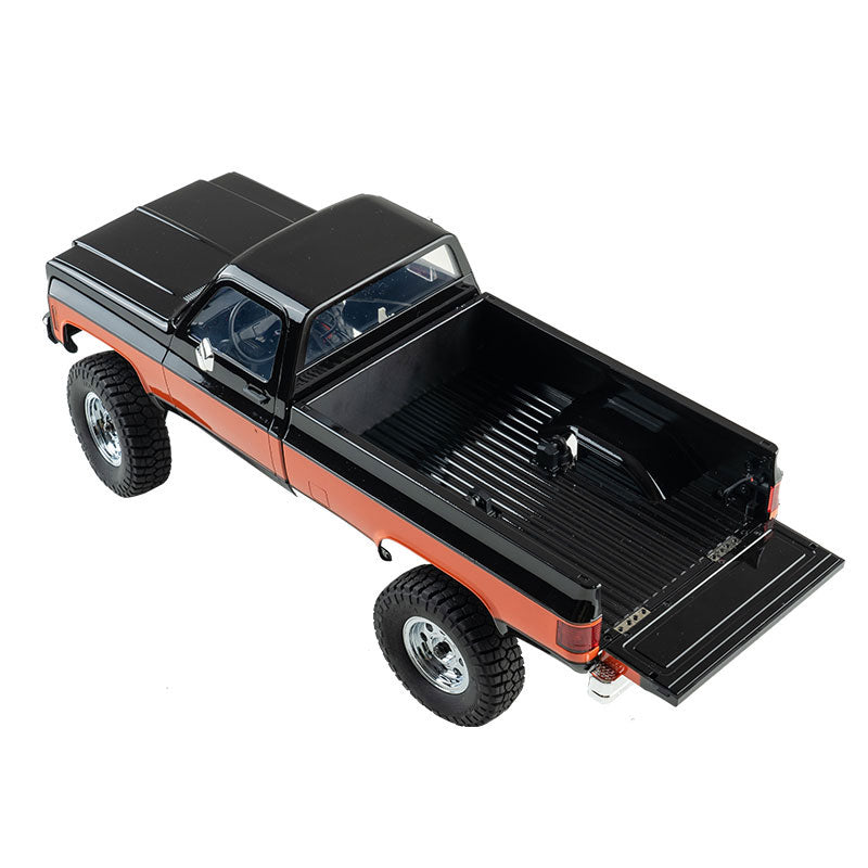 FMS 1:18 FCX18 Chevrolet K10 V2 RTR pickup truck in black and orange, with an open tailgate.