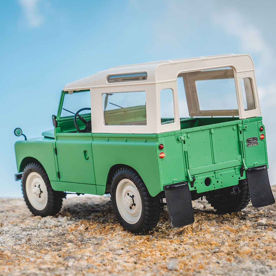 FMS 1:12 scale green Land Rover Series II RTR model with cream roof on rocky terrain