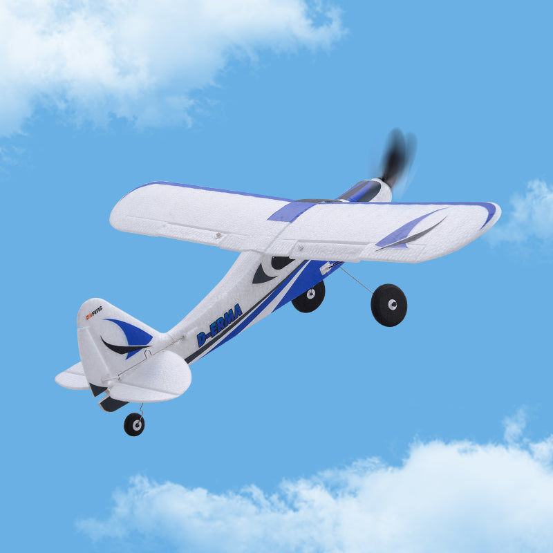 FMS 500mm PA-18 Super Cub RC plane flying in blue sky with clouds. White and blue design.