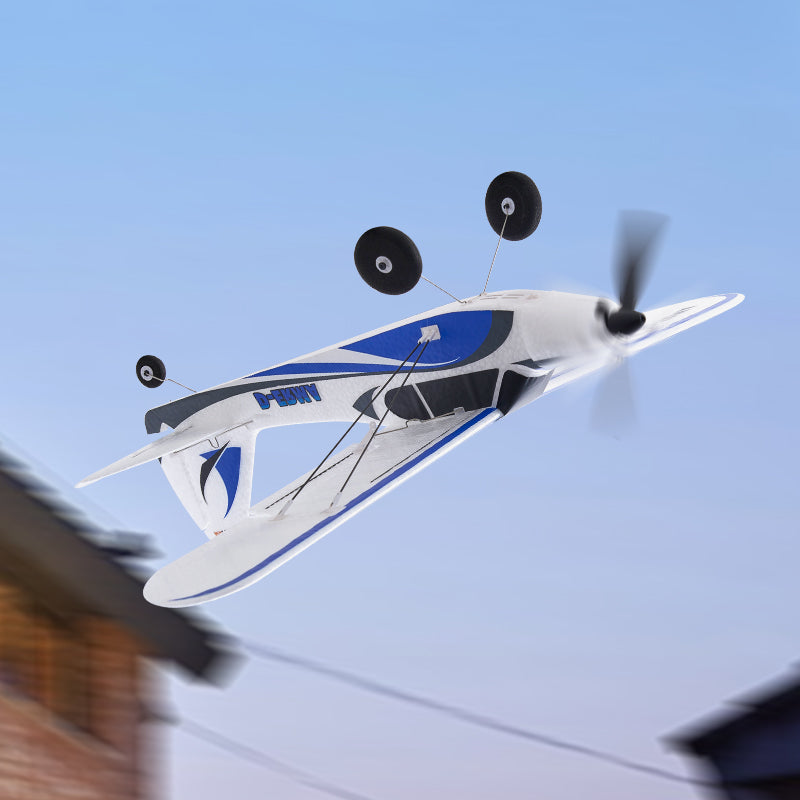 FMS 500mm PA-18 Super Cub RTF RC airplane flying, white with blue/grey accents, spinning prop, wheels down.