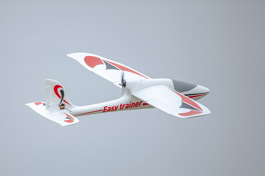 FMS 1280mm Easy Trainer RC airplane flying with red and black decals. Features pusher prop and "Easy trainer" text.