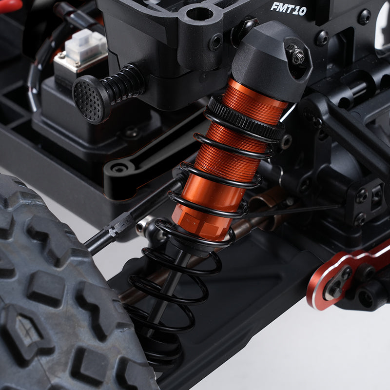 Orange oil-filled shock absorber with black coil springs on FMS 1:10 Colorado Basher RS.