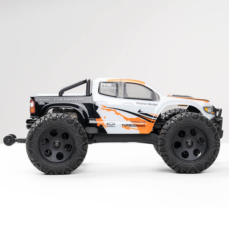 FMS 1:24 FMT24 Chevrolet Colorado Monster Truck RTR in white with orange and black graphics, featuring large off-road tires.