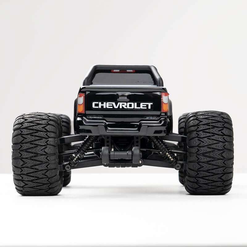 Black FMS 1:24 FMT24 Chevrolet Colorado monster truck rear view with large tires and suspension