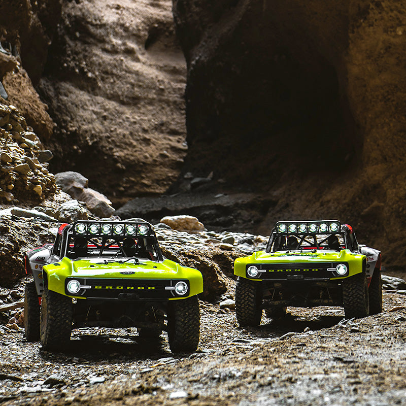 FMS 1:7 Ford Bronco RTR EB Brushless 4WD RS RC car in bright lime green, driving off-road through a rocky canyon.