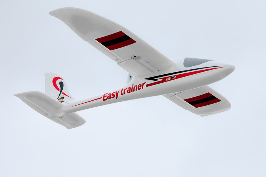 FMS 1280mm Easy Trainer RC plane, white with red and black accents, flying in the sky.