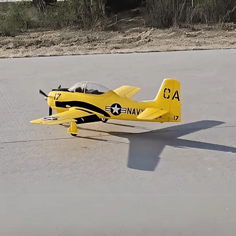 FMS 1400mm T-28D Trojan V4 Yellow PNP RC airplane taxiing on tarmac, featuring "NAVY" text and star insignia.