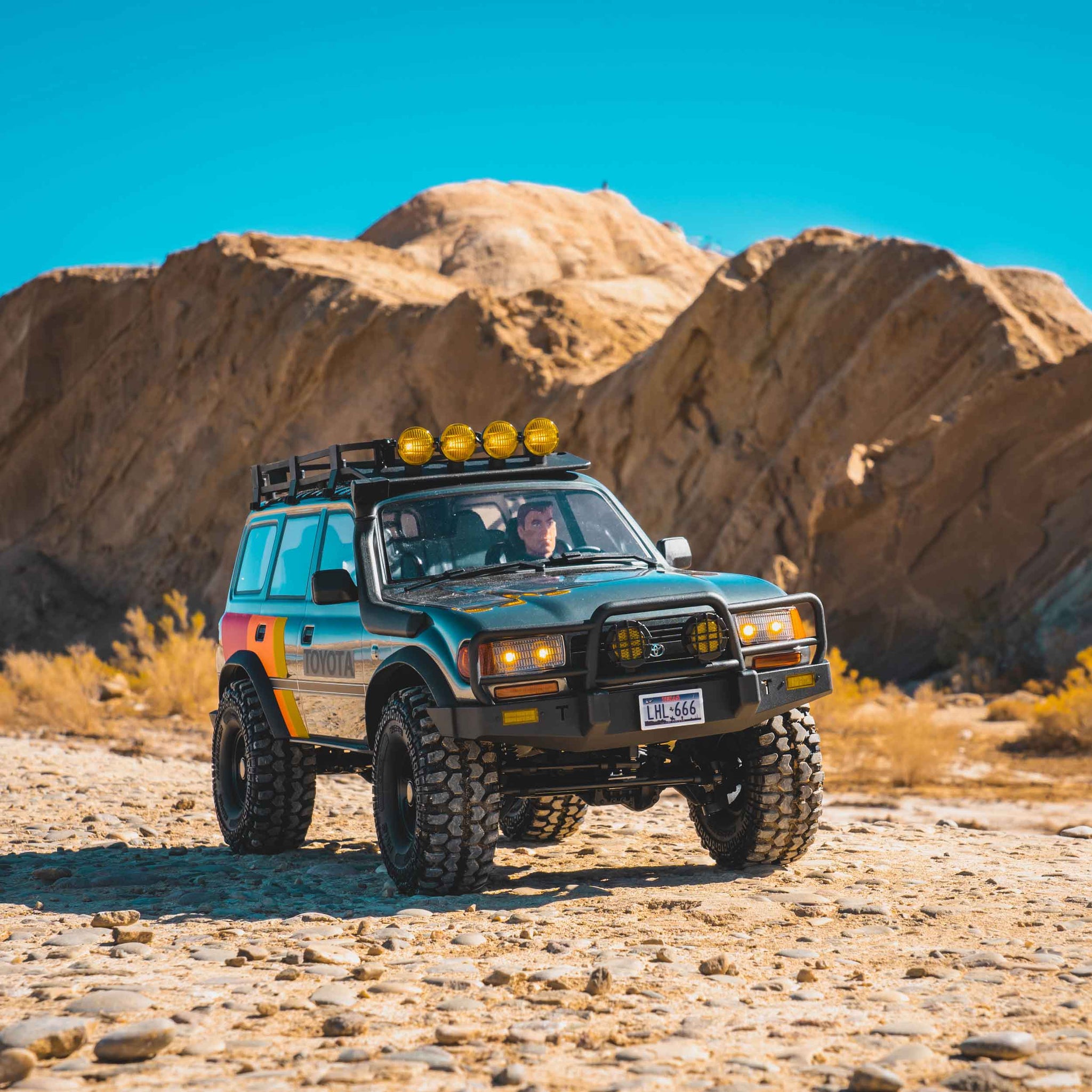 Fmshobby 1/10 scale FCX10 LC80 PRO RC crawler driving over rocky outdoor terrain