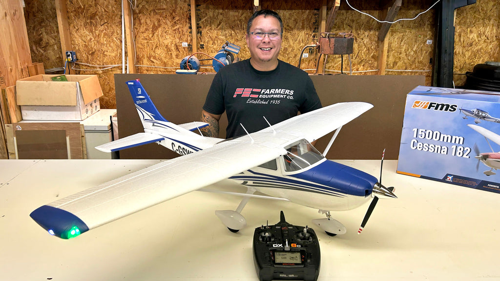 Workshop enthusiast displaying assembled FMS Cessna 182 model aircraft with Skylane livery