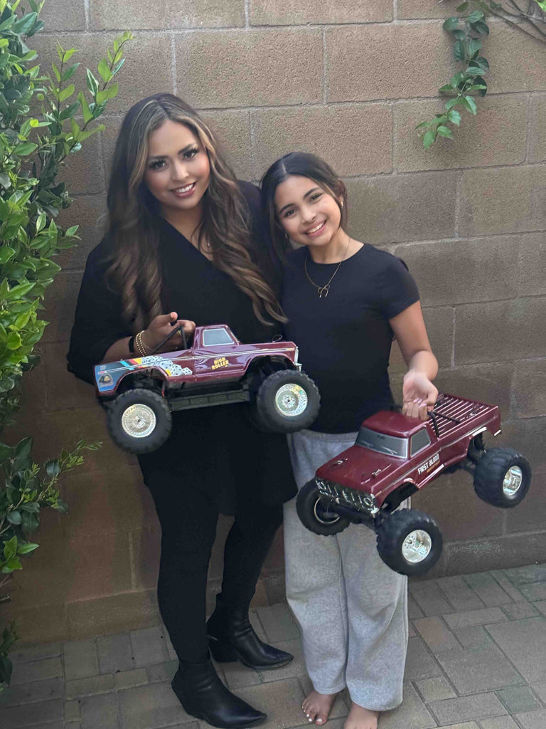 Madre e hija con camiones monstruo teledirigidos.