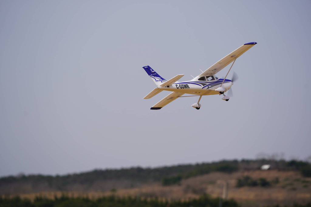 RC aircraft in flight over countryside landscape