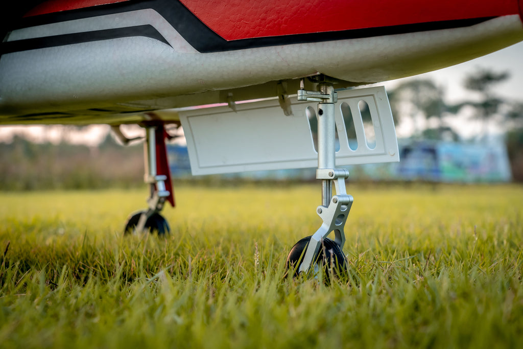 Close-up of the FMS Futura V3 durable metal landing gear and nose gear doors on a grass surface