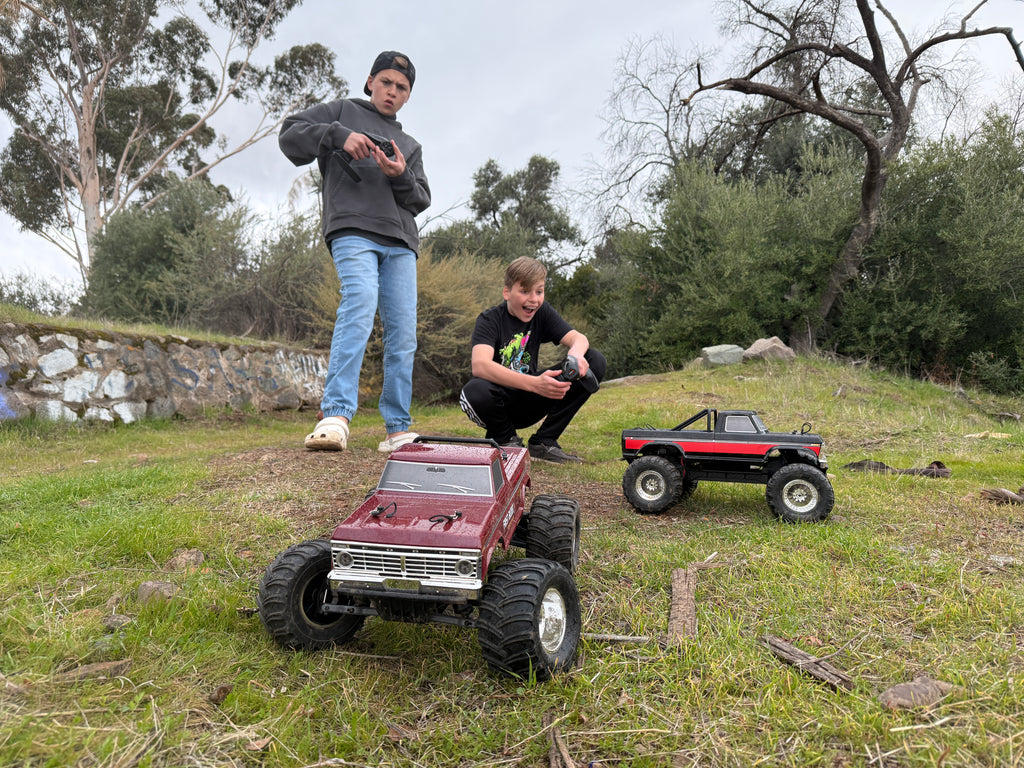 Two RC monster trucks on grassy terrain
