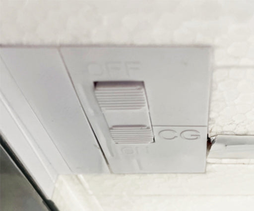 Close-up of a white toggle switch panel with markings "OFF" and "CG" showing the switch in a neutral position.