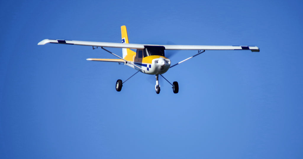 yellow and white RC Cessna-style aircraft in flight