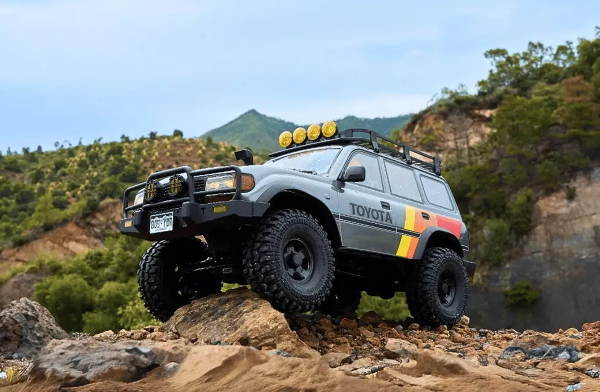 Grey FMS FCX10 LC80 Toyota Land Cruiser 1/10-scale RC crawler climbing rocky terrain on an outdoor trail