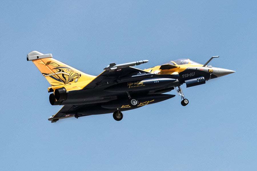 FMS 80mm Rafale jet, yellow/navy blue, tiger tail, in flight with landing gear extended. RC EDF model.