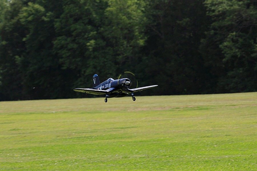 FMS 800mm F4U Corsair V2 RC airplane in flight over a grassy field.