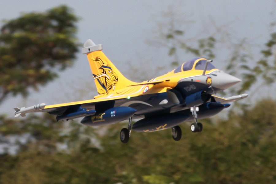 FMS 80mm Rafale jet with yellow and blue livery, landing gear down, in flight.