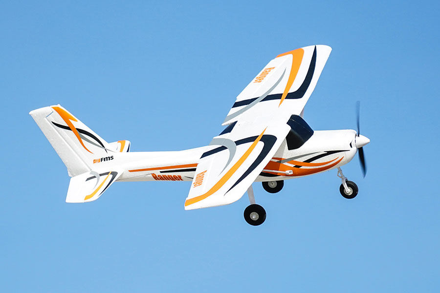 FMS 850mm Ranger RC airplane flying in blue sky with orange and black accents.