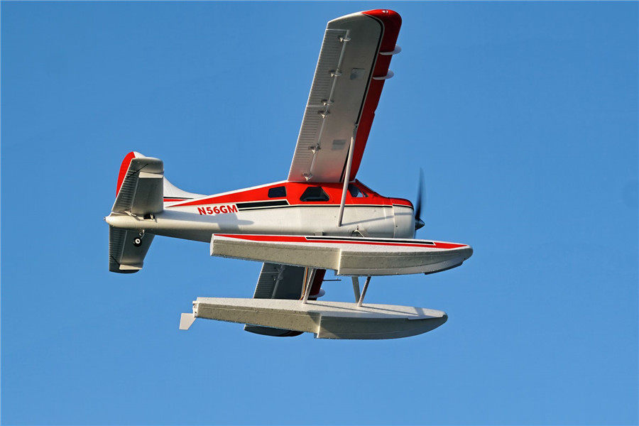 FMS 2000mm Beaver V2 seaplane with red and white trim flying in blue sky, registration N56GM.
