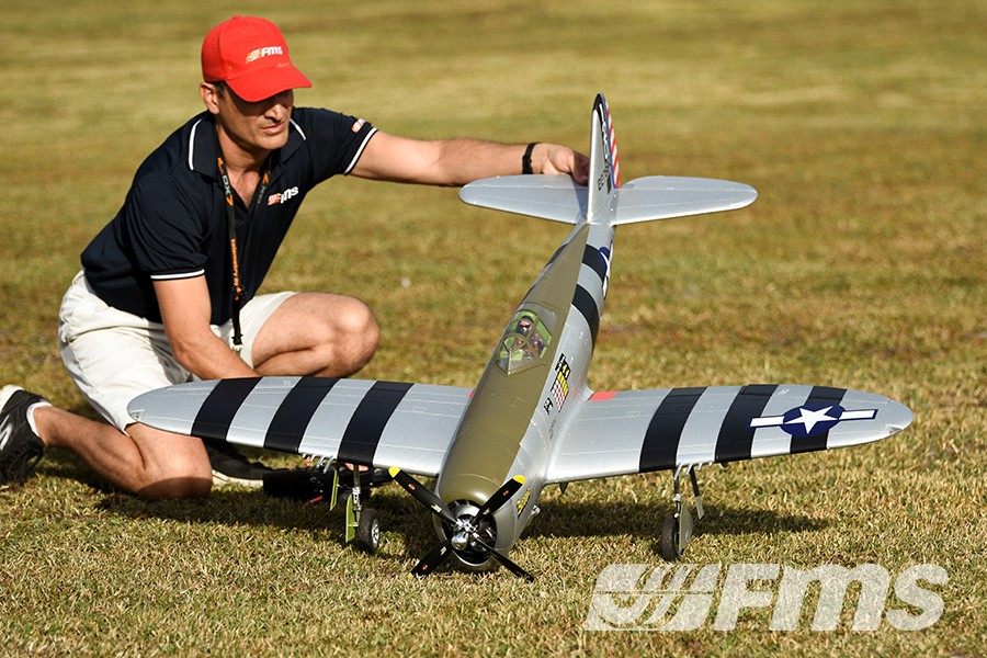 FMS 1500mm P-47 Thunderbolt Bonnie PNP RC airplane with a man presenting it on grass.