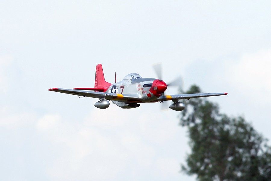 FMS 1700mm P-51D Red Tail Mustang PNP model in flight, featuring silver body, red tail and spinner, and detailed markings.