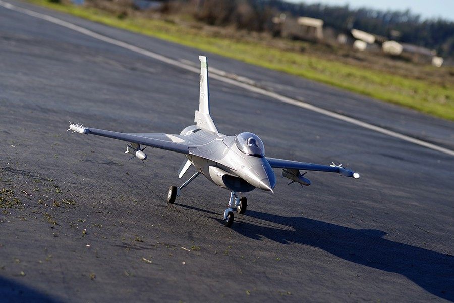 FMS 70mm F-16C Fighting Falcon RC jet model on tarmac, grey camouflage, ready for takeoff.