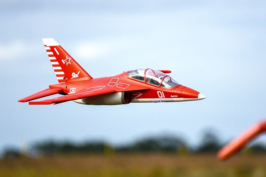 FMS Yak-130 V2 EDF Jet, PNP model aircraft in red, flying against a blue sky with numbered markings.