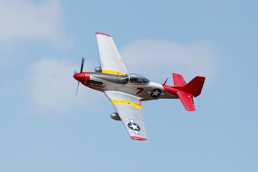 FMS 1700mm P-51D Red Tail PNP model airplane in flight with silver fuselage, red tail, and yellow wing accents.